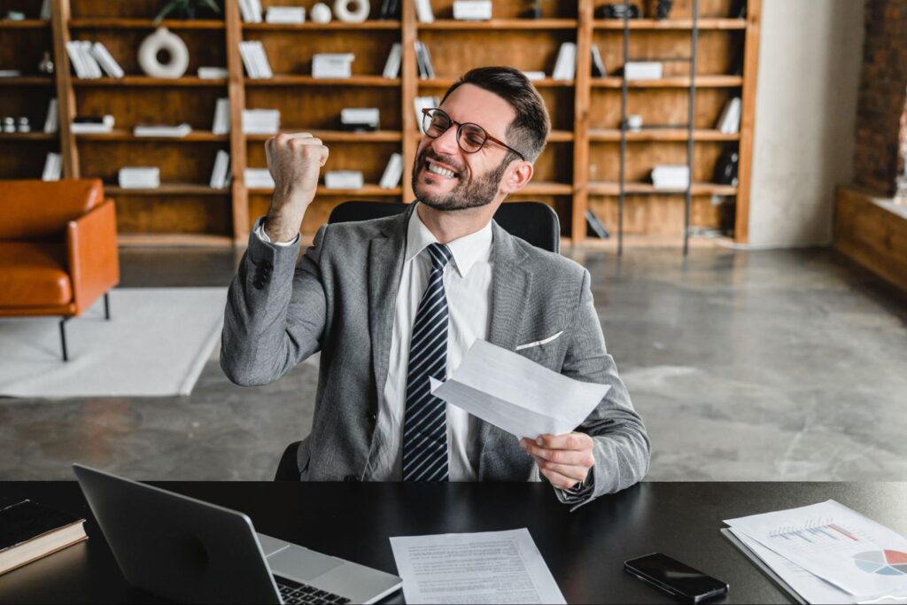 Successful business professional celebrating in office, demonstrating the benefits of effective lease abstract management in commercial real estate.