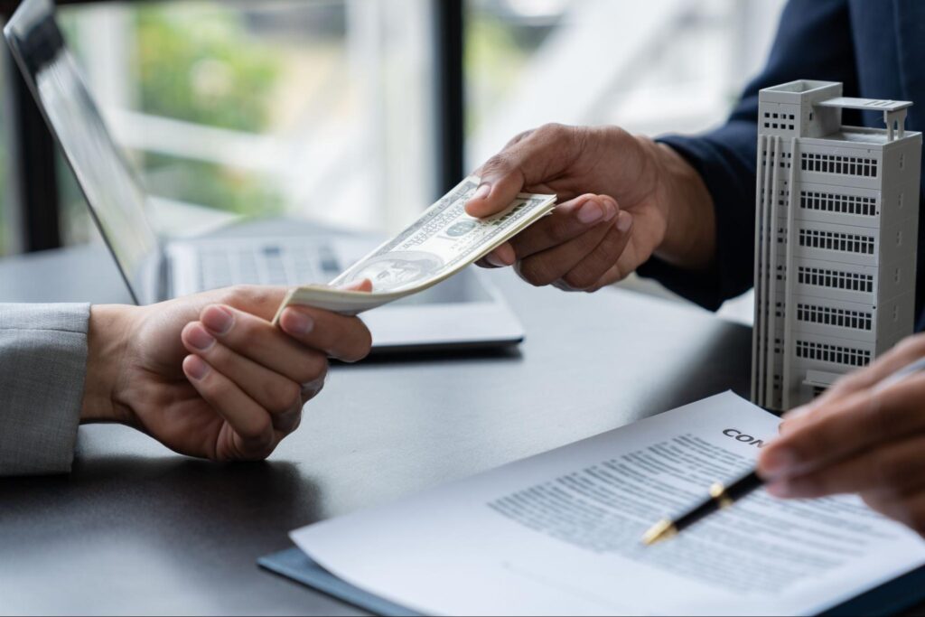 Close-up of two professionals exchanging money, symbolizing a business transaction or investment.