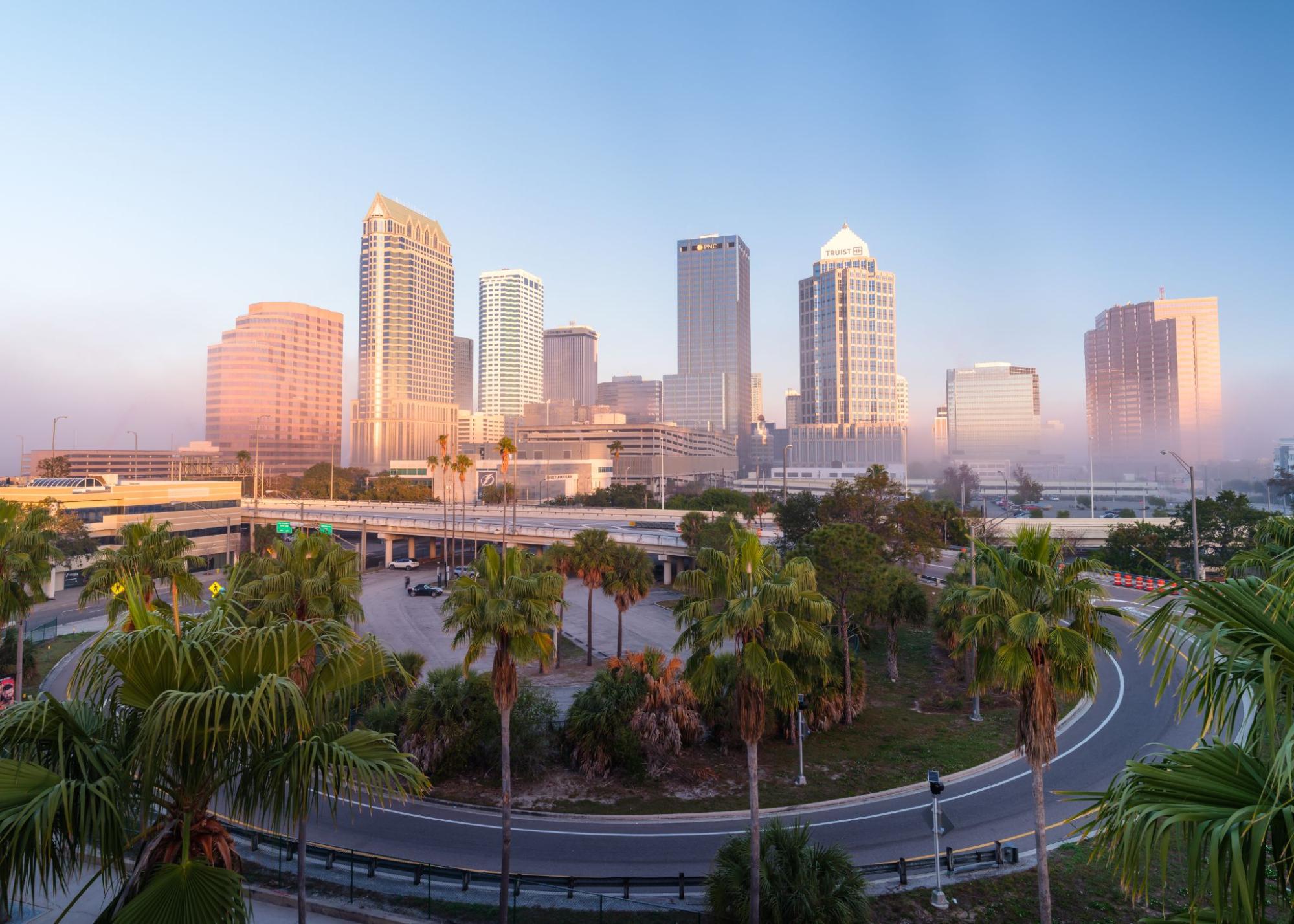 A semi-aerial view of downtown Tampa showcasing curved roads and towering skyscrapers under clear daylight.