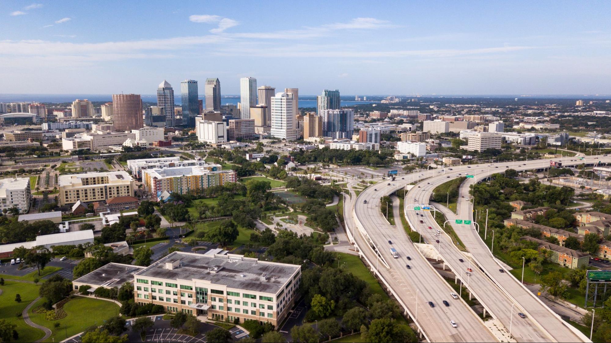 Aerial view of downtown Tampa showing busy roads and modern skyscrapers on a bright day.