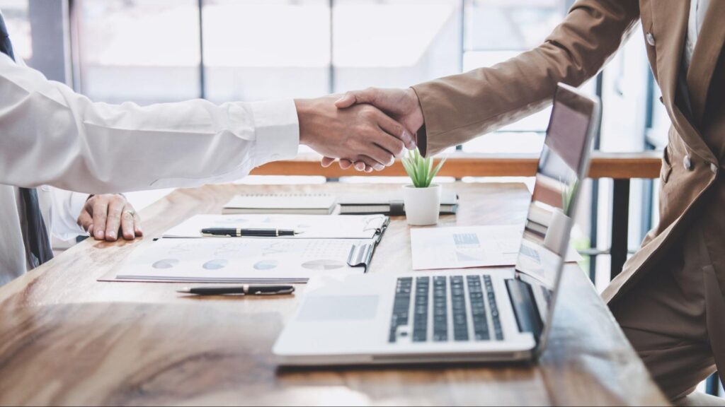 Handshake between investors finalizing a real estate financing deal in a modern workspace.